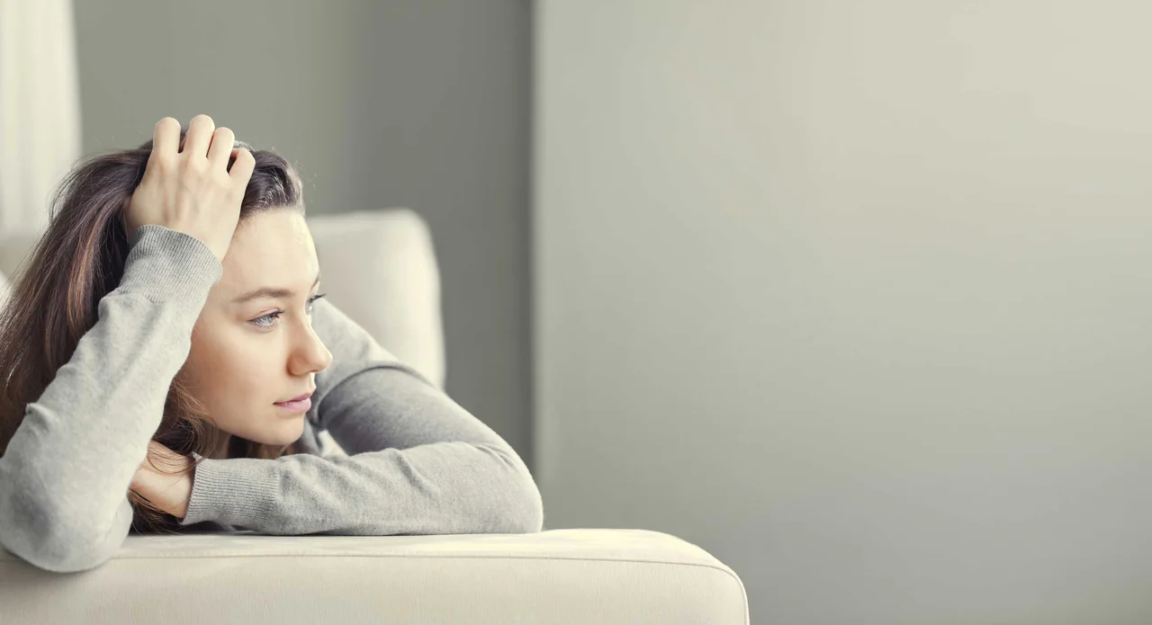 frau-schaut-in-die-ferne-auf-sofa