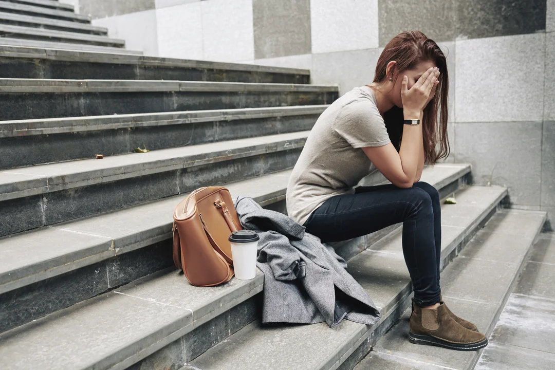 frau-sitzt-auf-treppe-mit-haenden-vor-gesicht