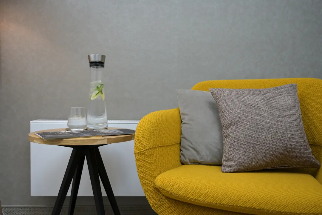 gelbes-sofa-graues-kissen-beistelltisch-wasserkaraffe