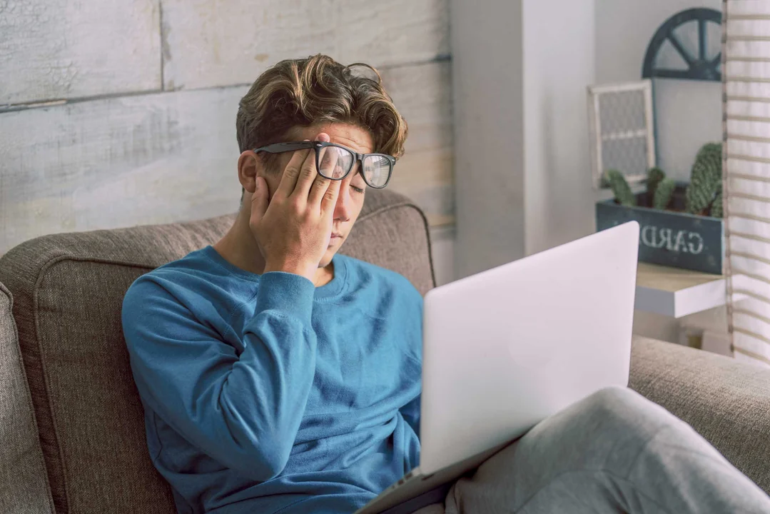 mann reibt sich die augen mit laptop
