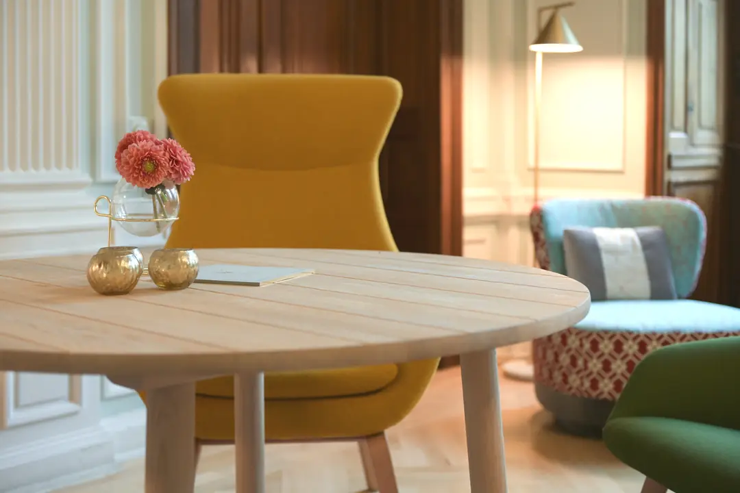 runder-holztisch-gelber-sessel-blumenvase-lounge